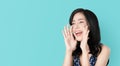 Attractive young asian woman announcing with hands to the mouth  and telling a secret, isolated on light blue background. Royalty Free Stock Photo