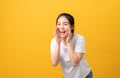 Attractive young asian woman announcing with hands to the mouth and telling a secret, isolated on light orange background. Royalty Free Stock Photo