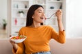 Attractive young asian woman eating vegetable salad at home Royalty Free Stock Photo