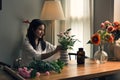 Attractive young Asian woman focuses on arranging a vase with beautiful flowers Royalty Free Stock Photo