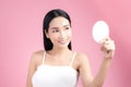 Attractive young Asian woman holding mirror and feeling happy about her skin. Isolated on pink background Royalty Free Stock Photo