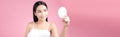 Attractive young Asian woman holding mirror and feeling happy about her skin. Isolated on pink background Royalty Free Stock Photo