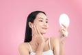 Attractive young Asian woman holding mirror and feeling happy about her skin.  on pink background Royalty Free Stock Photo