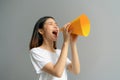 Attractive young Asian woman holding paper megaphone and yelling into. Royalty Free Stock Photo