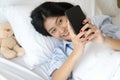 Attractive asian woman holding smart phone and take photo lying on the white bed in the morning. Focus close up people hands Royalty Free Stock Photo