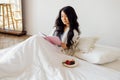 Asian woman is lying in bed reading a book and eating berries Royalty Free Stock Photo