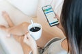 Attractive young Asian woman relaxing on sofa at home in the morning while have some coffee and using smartphone. Technology and Royalty Free Stock Photo