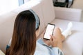 Attractive young Asian woman relaxing on sofa at home and using smartphone. Top view with copy space Royalty Free Stock Photo