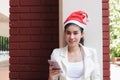 Attractive young Asian woman with santa hat using mobile smart phone for shopping online for christmas gifts Royalty Free Stock Photo