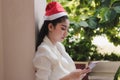 Attractive young Asian woman with santa hat using mobile smart phone for shopping online for christmas gifts Royalty Free Stock Photo