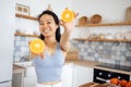 An attractive young Asian woman smiles and shows oranges to the camera. A beautiful Thai girl prepares a healthy breakfast with Royalty Free Stock Photo