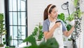 Attractive Young Asian woman taking care Water the household plants pots near window, Gardening at Home concept Royalty Free Stock Photo