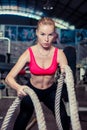 An attractive young and athletic girl using training ropes in a gym. Royalty Free Stock Photo