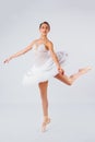 Attractive young ballerina with a beautiful body in leotard dancing tiptoes in photostudio isolated on white background. Showing Royalty Free Stock Photo