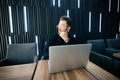 Attractive young bearded man in suit looking away while sitting at office desk with laptop and other items Royalty Free Stock Photo