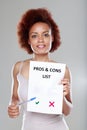 Attractive young Black woman holding a Pros and Cons list Royalty Free Stock Photo