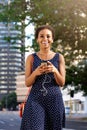 Attractive young black woman walking in city with mobile and earphones Royalty Free Stock Photo