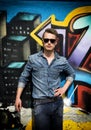 Attractive young blond man against colorful graffiti wall