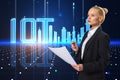 Attractive young blonde businesswoman with creative glowing digital mesh city and iot hologram standing on blurry background. Royalty Free Stock Photo