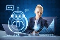 Attractive young blonde businesswoman doing paperwork at desktop with laptop and glowing robot and chart on blue background.