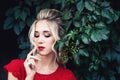 Attractive young blonde girl in red dress posing near a wild vineyard. Royalty Free Stock Photo