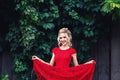 Attractive young blonde girl in red dress posing near a wild vineyard. Royalty Free Stock Photo