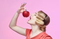 Attractive young blonde with a retro hairstyle is about to bite a red apple Royalty Free Stock Photo