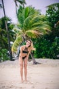 Attractive young blonde woman in bikini standing on sandy beach on windy day Royalty Free Stock Photo