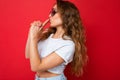 Attractive young blonde woman wearing everyday stylish clothes and modern sunglasses  on colorful background Royalty Free Stock Photo