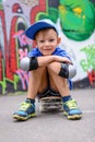 Attractive young boy sitting on his skateboard Royalty Free Stock Photo