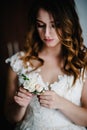 Attractive young bride holding the groom`s buttonhole. flowers with pink roses, white carnation and green and greens. Bride`s