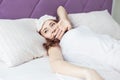 An attractive young brunette girl with brown hair wakes up and sips while yawning in her bed in a sleep mask Royalty Free Stock Photo