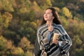 Attractive young brunette woman in a poncho with a coffee in hand. Girl looks at the sky and smiling Royalty Free Stock Photo