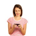 Attractive young brunette woman using her cell phone to send a text message or play the game. emotional girl isolated on white bac Royalty Free Stock Photo