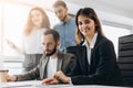 Attractive young business lady is looking at camera and smiling while her colleagues are working in the background Royalty Free Stock Photo