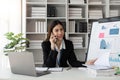 Attractive young business woman talking on the mobile phone and smiling while sitting at her working place in office and Royalty Free Stock Photo