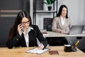 Attractive young business woman wearing jacket talking on mobile phone while sitting on a desk and using notebook near her Royalty Free Stock Photo
