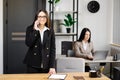 Attractive young business woman wearing jacket talking on mobile phone while sitting on a desk and using notebook near her Royalty Free Stock Photo