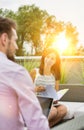 Attractive young business woman holding a file and smiling whilst she has a meeting outside wth a colleague who is working on his Royalty Free Stock Photo