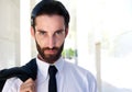 Attractive young businessman with beard standing outside