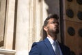 Attractive young businessman with beard and suit, leaning against a wall with face half light and half shadow. Concept beauty, Royalty Free Stock Photo