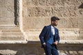 Attractive young businessman with beard and suit, posing leaning against a stone wall. Concept beauty, fashion, success, achiever