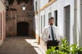 Attractive young businessman with beard, suit and tie, posing with hands in pockets behind green plants. Concept beauty, fashion, Royalty Free Stock Photo