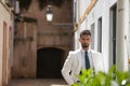 Attractive young businessman with beard, suit and tie, posing with hands in pockets behind green plants. Concept beauty, fashion, Royalty Free Stock Photo