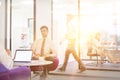 Attractive young businessman having job interview whilst people work in an active office in the background, job hunting concept