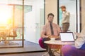 Attractive young businessman having job interview whilst people work in an active office in the background, job hunting concept