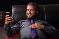 Attractive young businessman is relaxing on a couch and reading sms on his smart phone Royalty Free Stock Photo