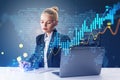 Attractive young businesswoman sitting and using laptop glowing candlestick forex chart on blurry blue background with map. Trade