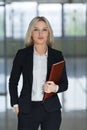 Attractive young businesswoman standing with folder in the office. Royalty Free Stock Photo