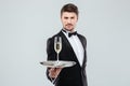 Attractive young butler in tuxedo offers you glass of champagne Royalty Free Stock Photo